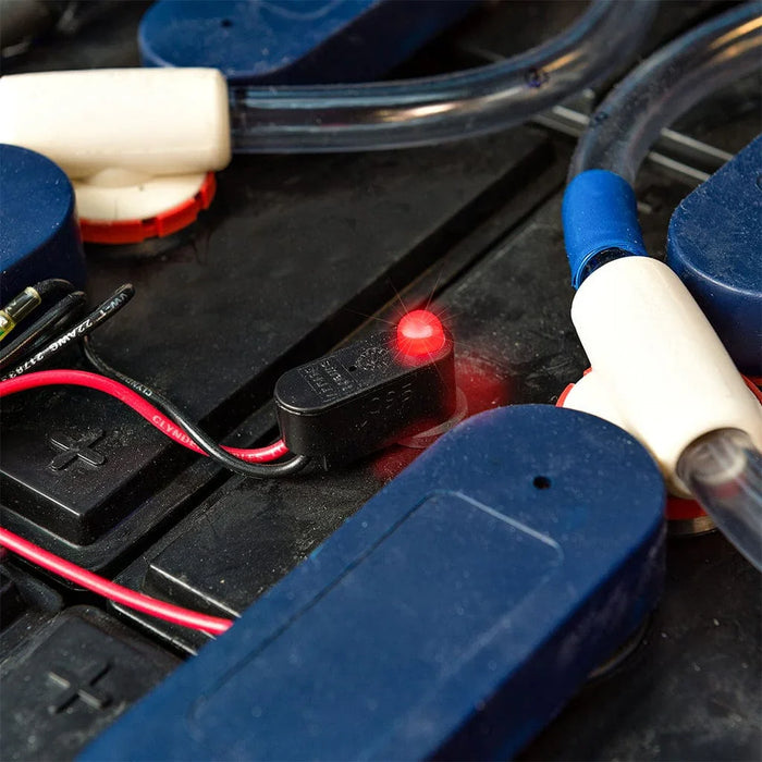 Battery watering monitor with red LED indicator on industrial battery setup